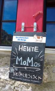 Kreideschild An Einen Fensterladen Der Ravensburger Hütte Angehängt, Auf Dem Steht: Heute Momos, Nepalesisch - Wir Verwenden Regionale Produkte. 16,90 €