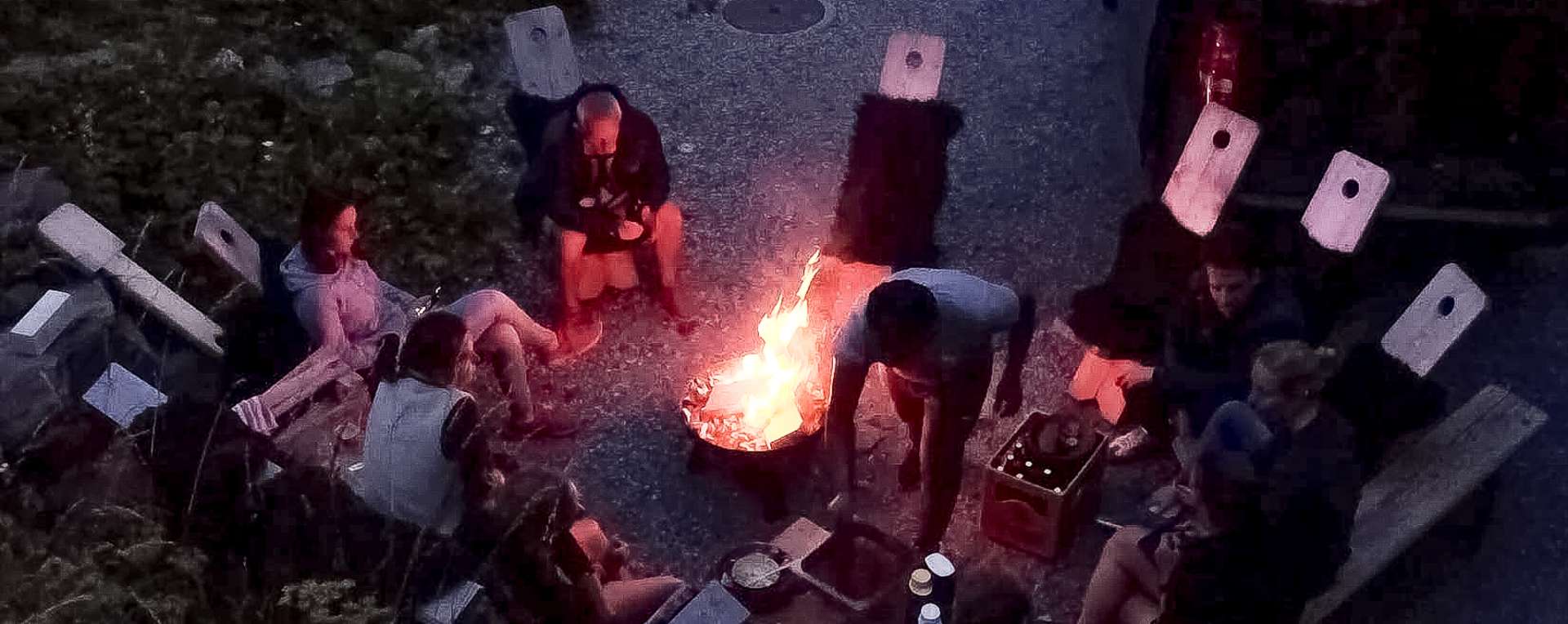 Mehrere Menschen sitzen bei Nacht um ein Lagerfeuer