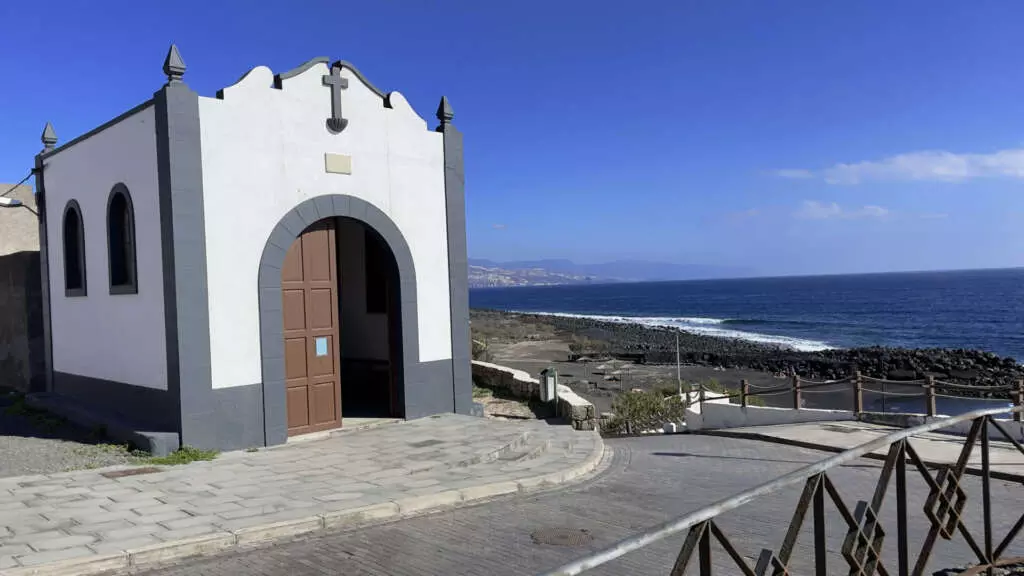 Eine kleine, weiße einstöckige Kirche, deren Doppeltür halboffen steht.